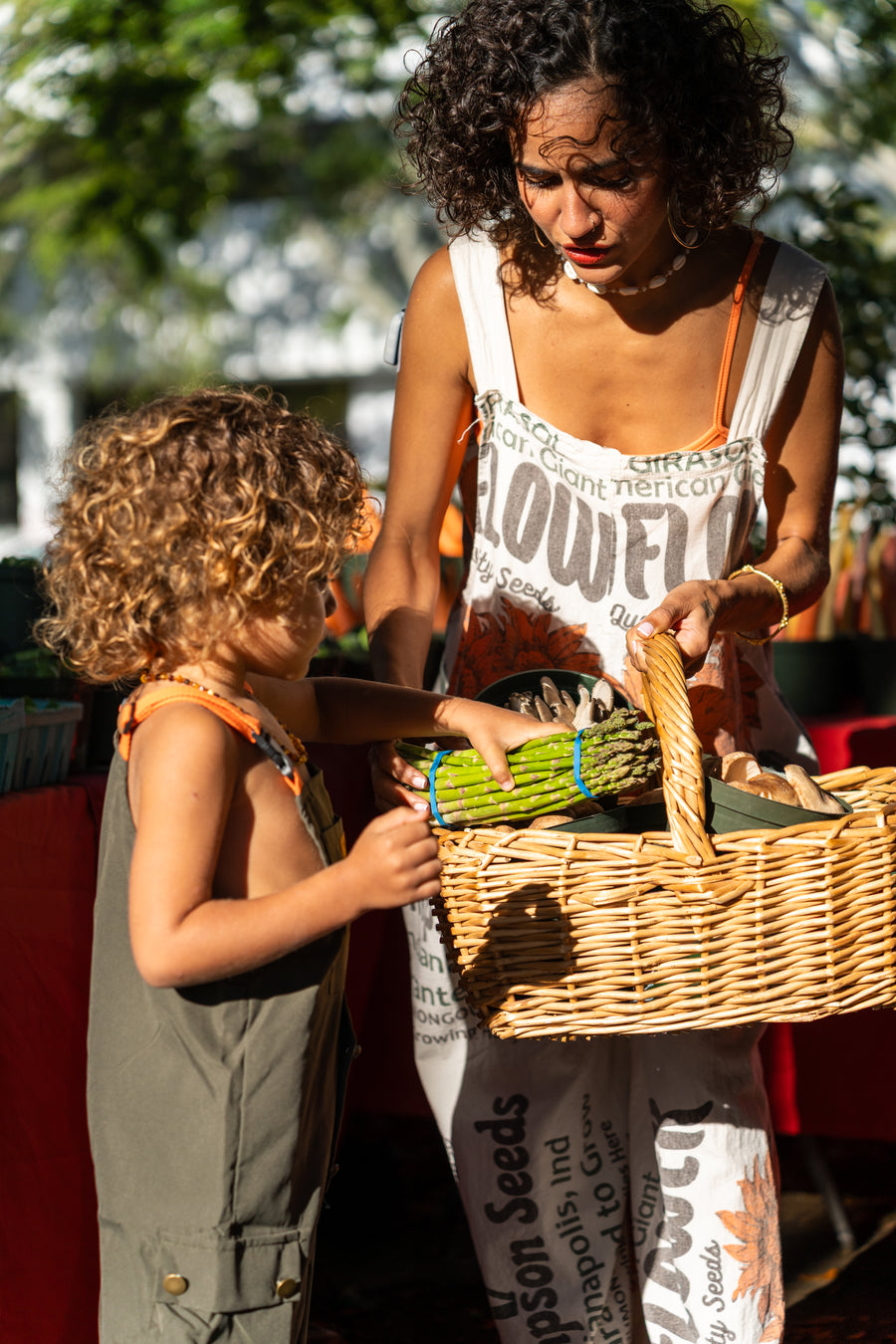 Hannah Chehab passing fresh herbs to her child at the farmer's market