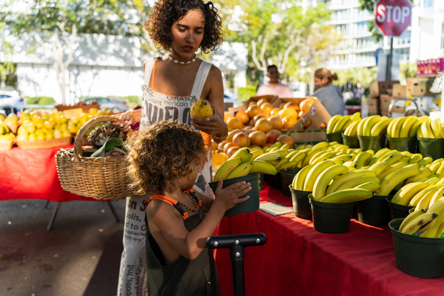 Hannah Chehab and her child choosing fresh fruit at the market stand
