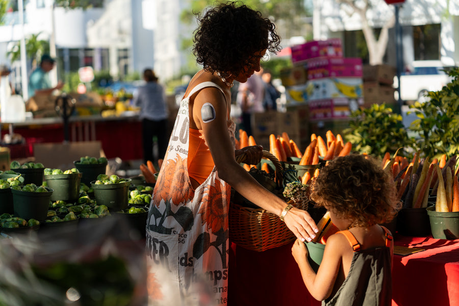 Hannah Chehab and her child at a farmer's market vegetable stall