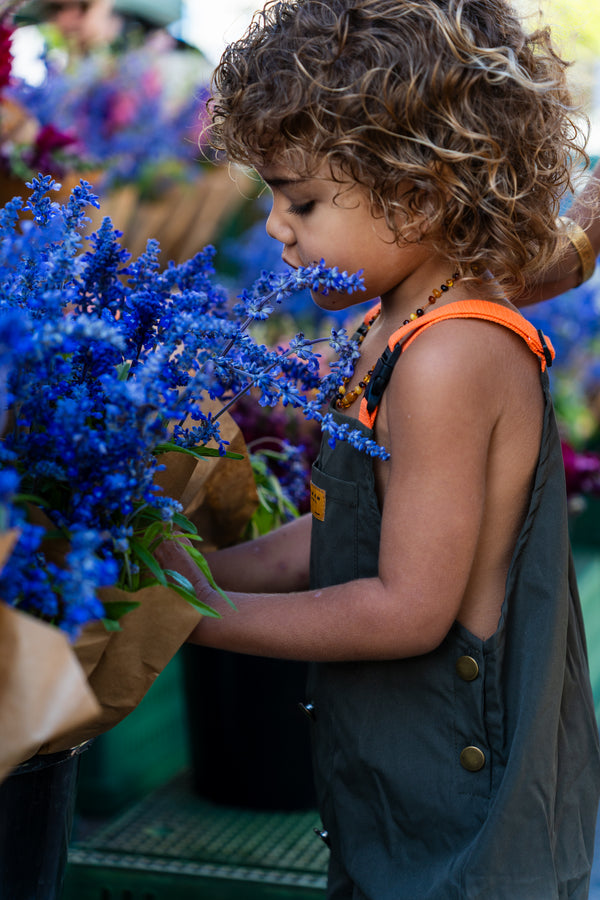 Young child smelling blue flowers — natural curiosity for herbal medicine