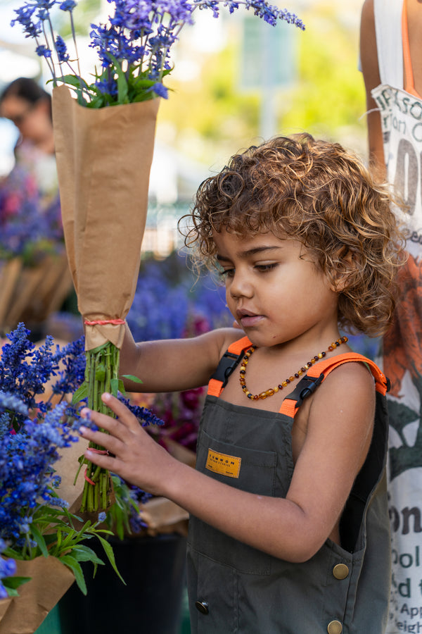 Young child exploring blue herbal flowers at the market